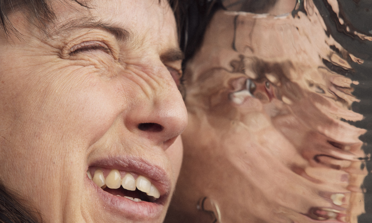 Kvinnas ansikte som upptryckt mot en spegel där spegelbilden har som ringar på vatten.