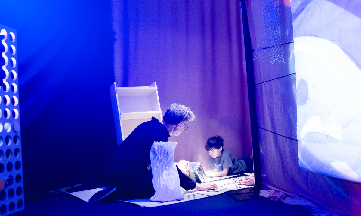 En skådespelare sitter med ett barn i ett scensoriskt rum
