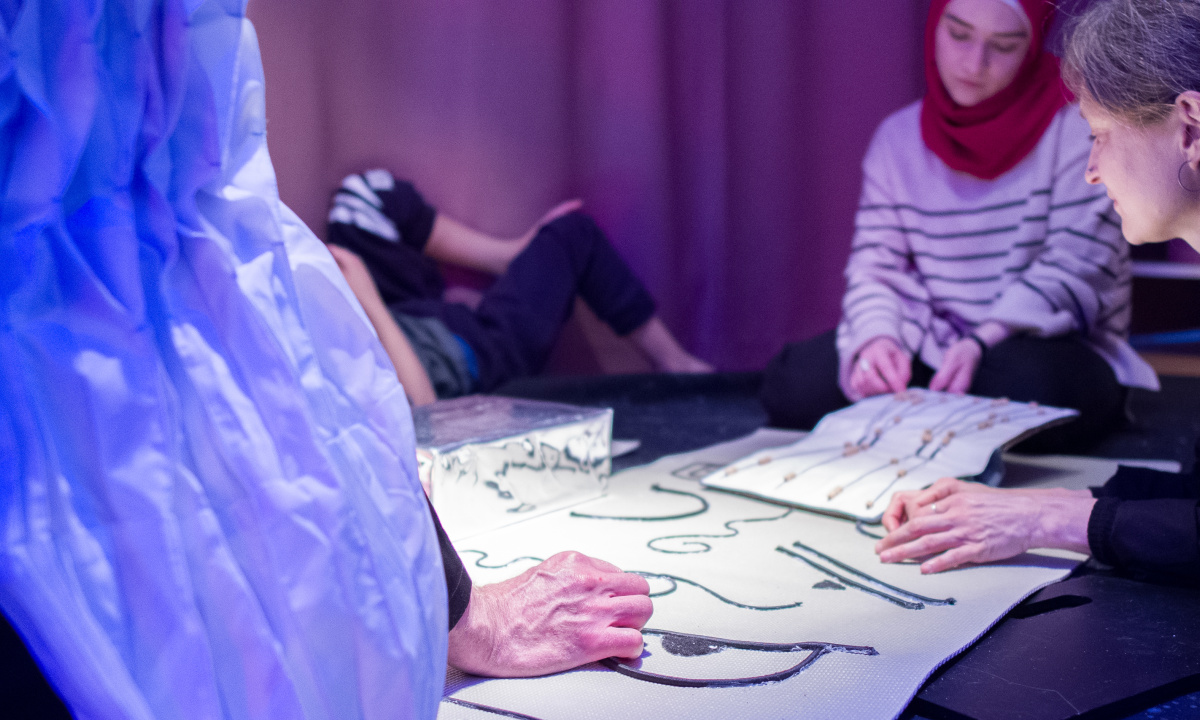 Barn känner på ett papper med saker fästa på det